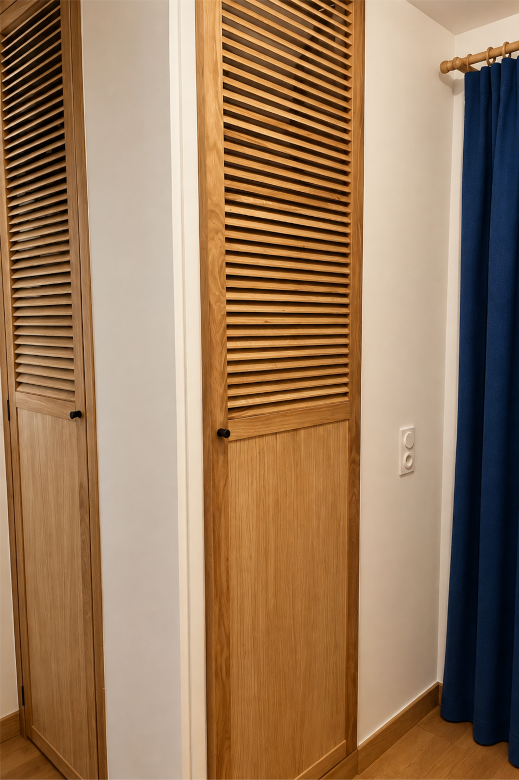 Portes de placard à persiennes en chêne massif avec boutons noirs.